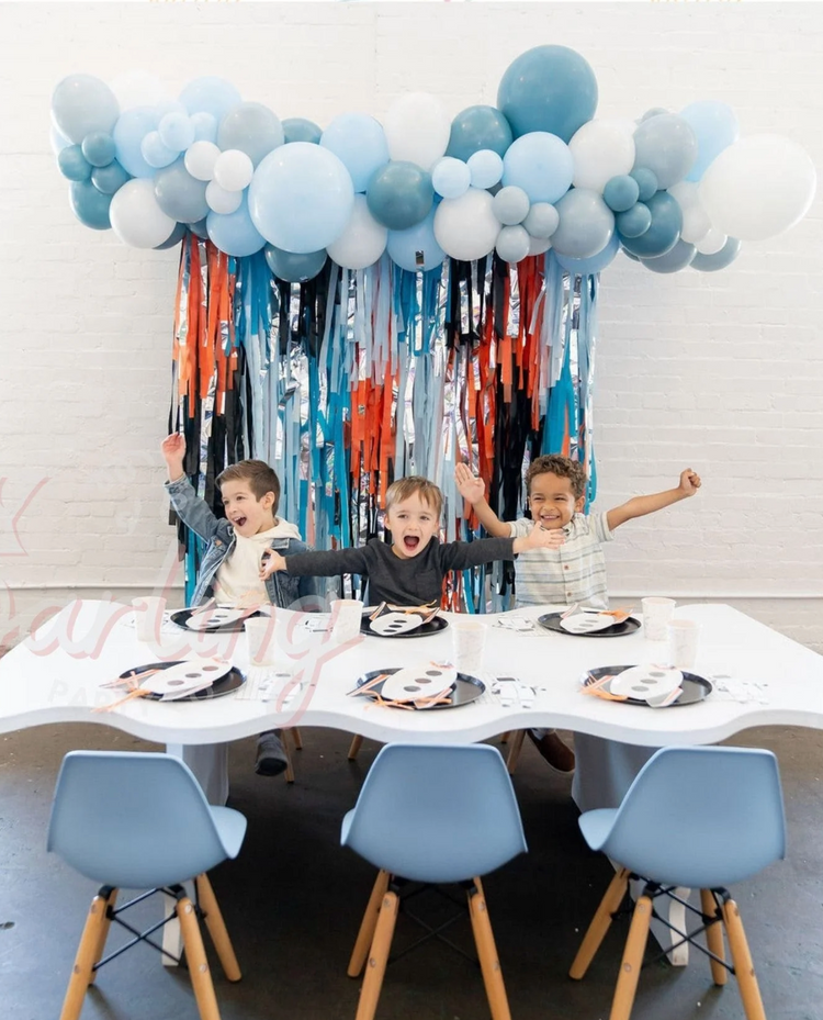 Blue and orange fringe party backdrop and balloon garland for boy's birthday by Oh My Darling Party Co
