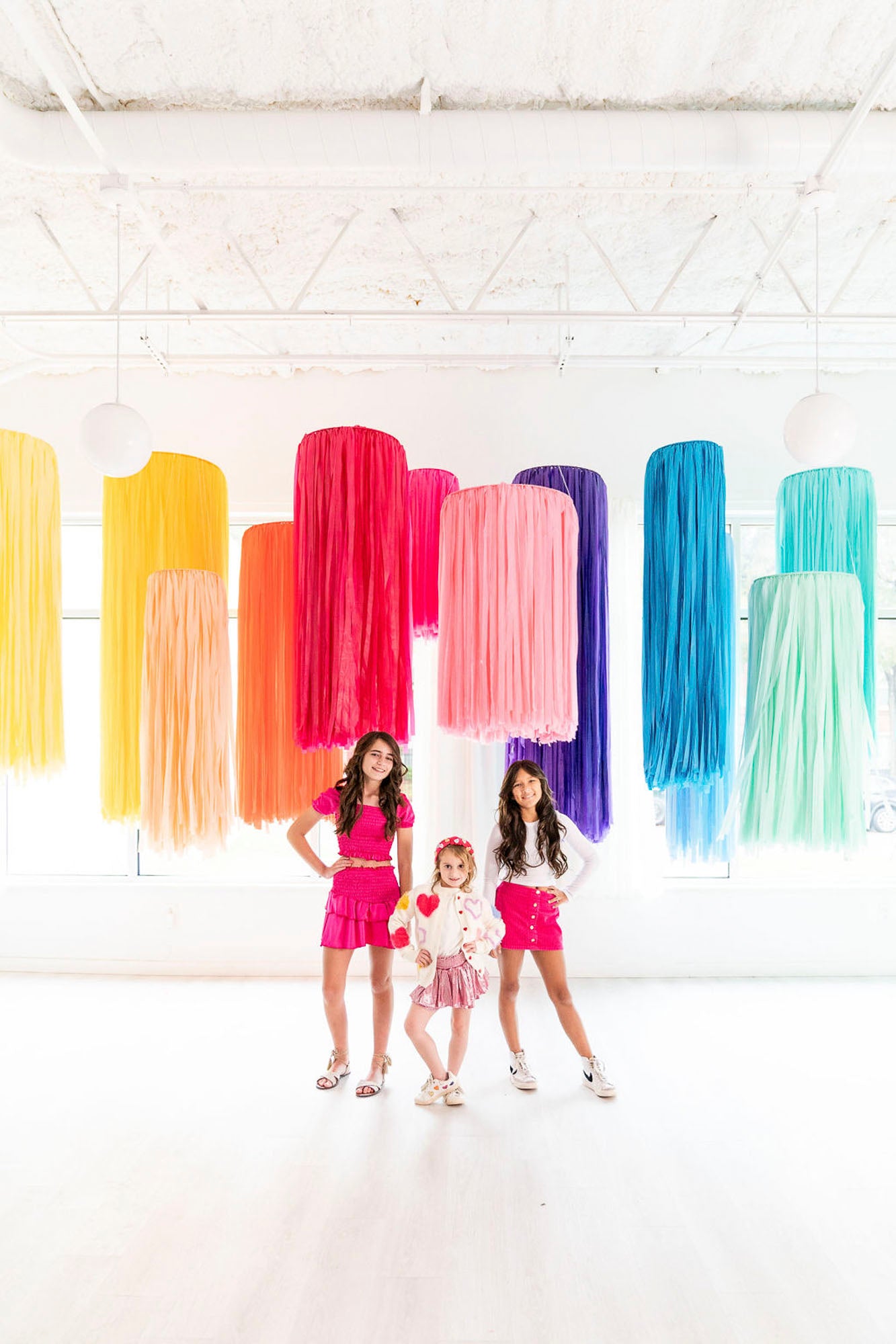 Girls posing in front of rainbow fringe aerial rings by Oh My Darling Party Co