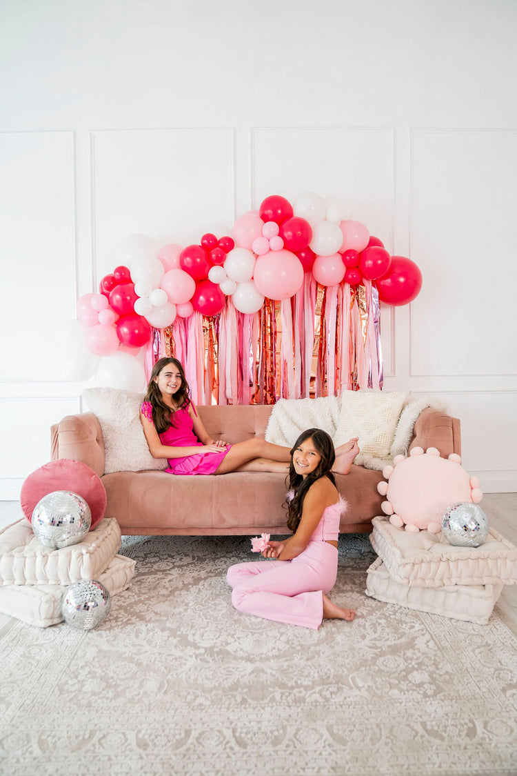 Teen girls in front of disco balls and pink and gold fringe backdrop and balloon garland by Oh My Darling Party Co