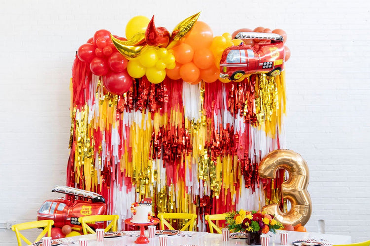 Firetruck themed fringe party backdrop and balloon garland for boy's birthday by Oh My Darling Party Co