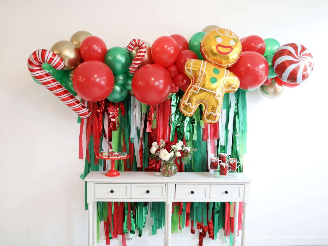 Festive Christmas fringe backdrop with balloons, candy canes, and a gingerbread man for holiday celebrations.