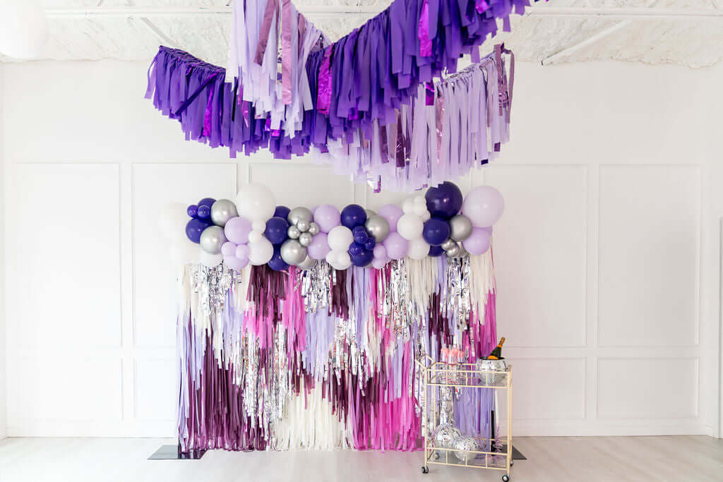 Purple fringe backdrop with balloons and silver accents, perfect for event decor and adding glamour.