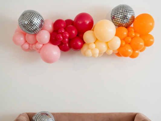 Let's Disco Balloon Kit fringe garland hanging against a white wall with balloons. Fringe decor perfect for corporate events or parties.