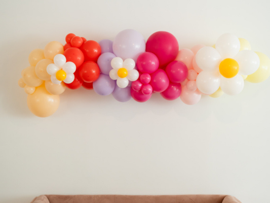 Peace, Love & Vibes Balloon Kit fringe garland hanging against a white wall with balloons. Fringe decor perfect for corporate events or parties.