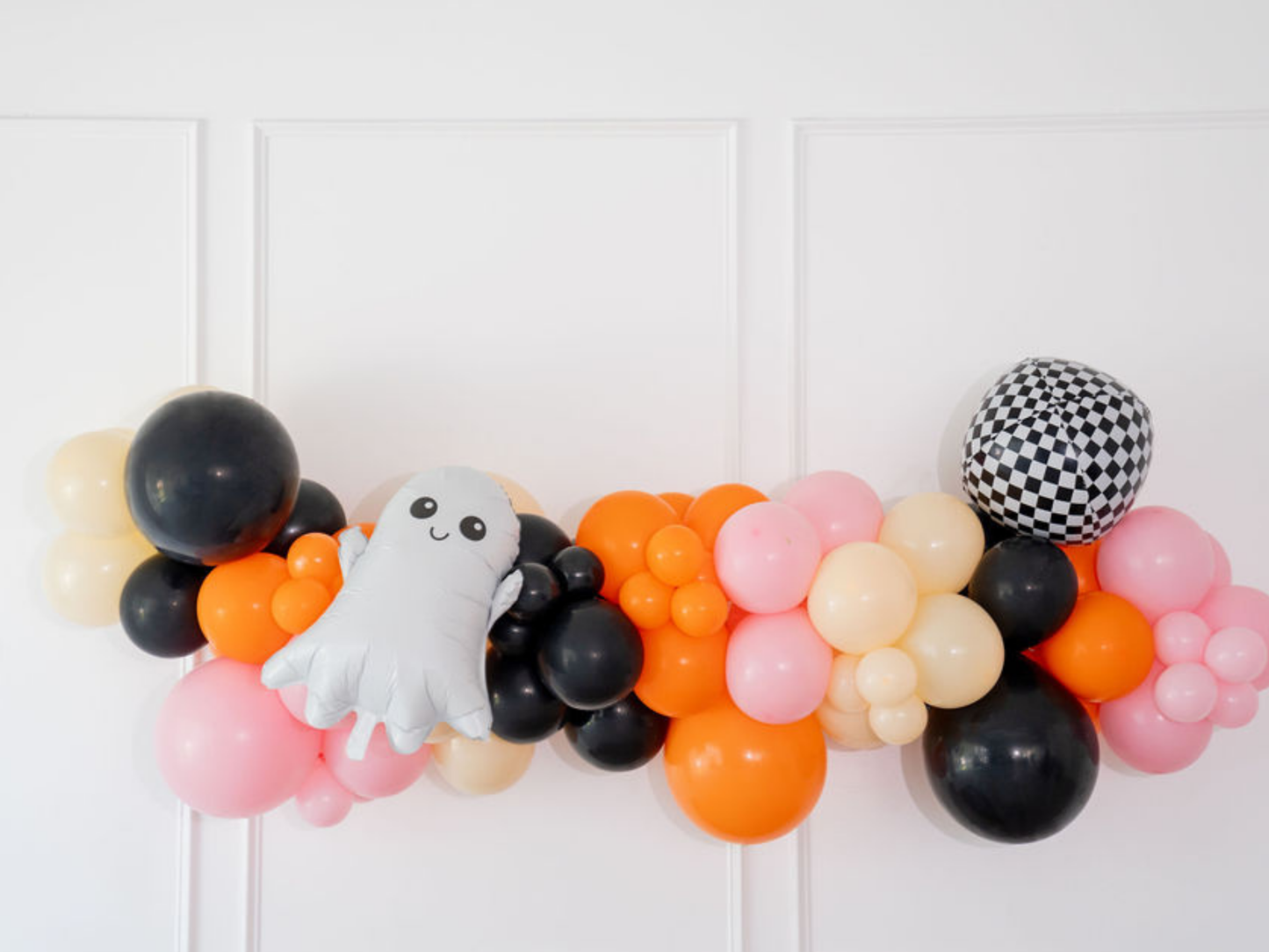 Ghouls Wanna Have Fun Balloon Kit fringe garland hanging against a white wall with balloons. Fringe decor perfect for corporate events or parties.