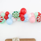 Merry & Bright Balloon Kit fringe garland hanging against a white wall with balloons. Fringe decor perfect for corporate events or parties.