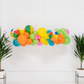 Beach Days Balloon Kit fringe garland hanging against a white wall with balloons. Fringe decor perfect for corporate events or parties.