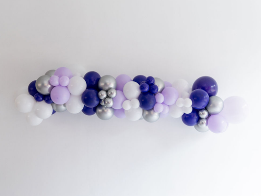 Purple & Silver Balloon Kit fringe garland hanging against a white wall with balloons. Fringe decor perfect for corporate events or parties.