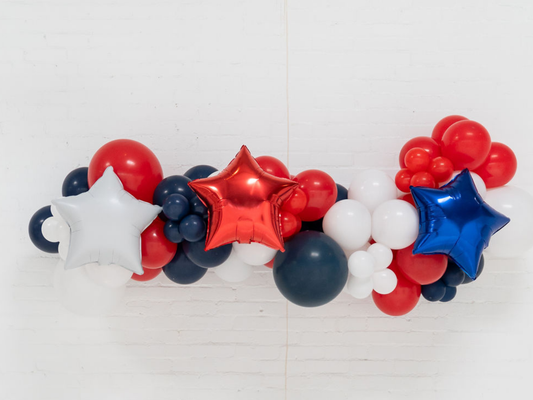 Star Spangled Balloon Kit fringe garland hanging against a white wall with balloons. Fringe decor perfect for corporate events or parties.