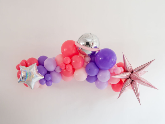 Stellar Balloon Kit fringe garland hanging against a white wall with balloons. Fringe decor perfect for corporate events or parties.