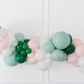 Pinkmas Balloon Kit fringe garland hanging against a white wall with balloons. Fringe decor perfect for corporate events or parties.