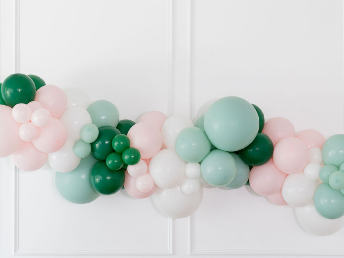 Pinkmas Balloon Kit fringe garland hanging against a white wall with balloons. Fringe decor perfect for corporate events or parties.