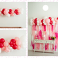 Pink Perfection Balloon Kit fringe garland hanging against a white wall with balloons. Fringe decor perfect for corporate events or parties.