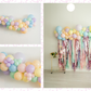 Pastel Balloon Kit fringe garland hanging against a white wall with balloons. Fringe decor perfect for corporate events or parties.