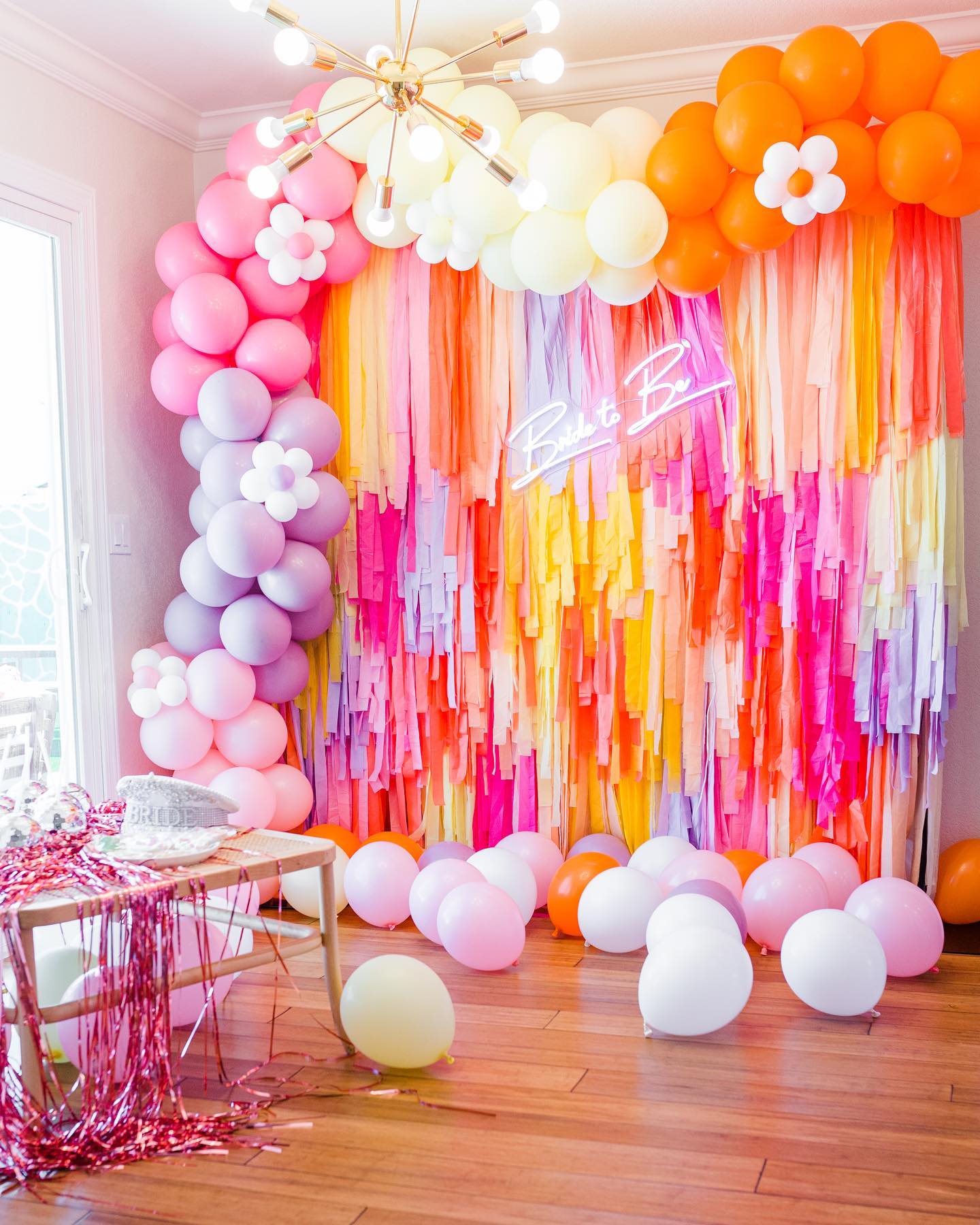 Pink, orange, and purple fringe backdrop and balloon garland party installation by Oh My Darling Party Co