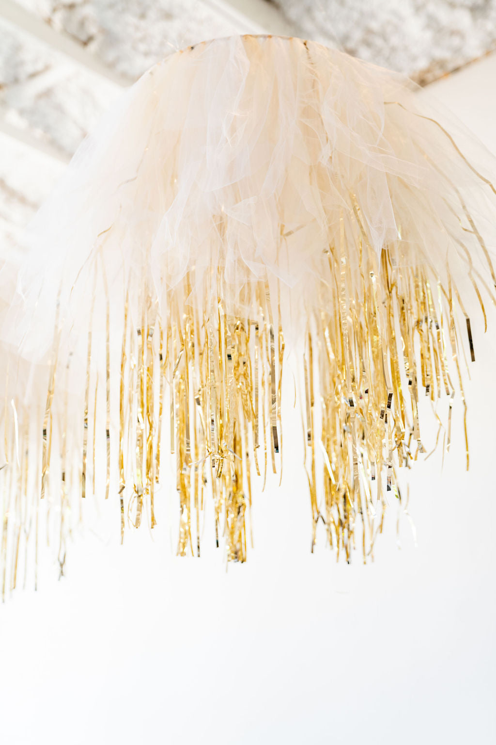 Tulle and tinsel aerial ring mixing soft fringe and metallic shine