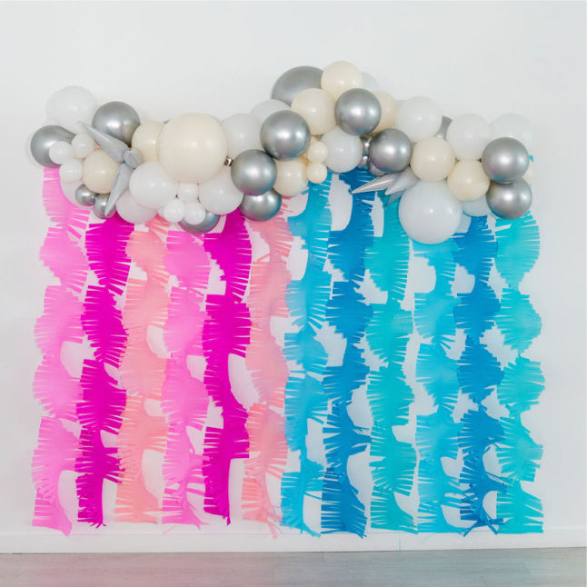 Pink and blue crepe paper streamer backdrop for gender reveal party by Oh My Darling Party Co