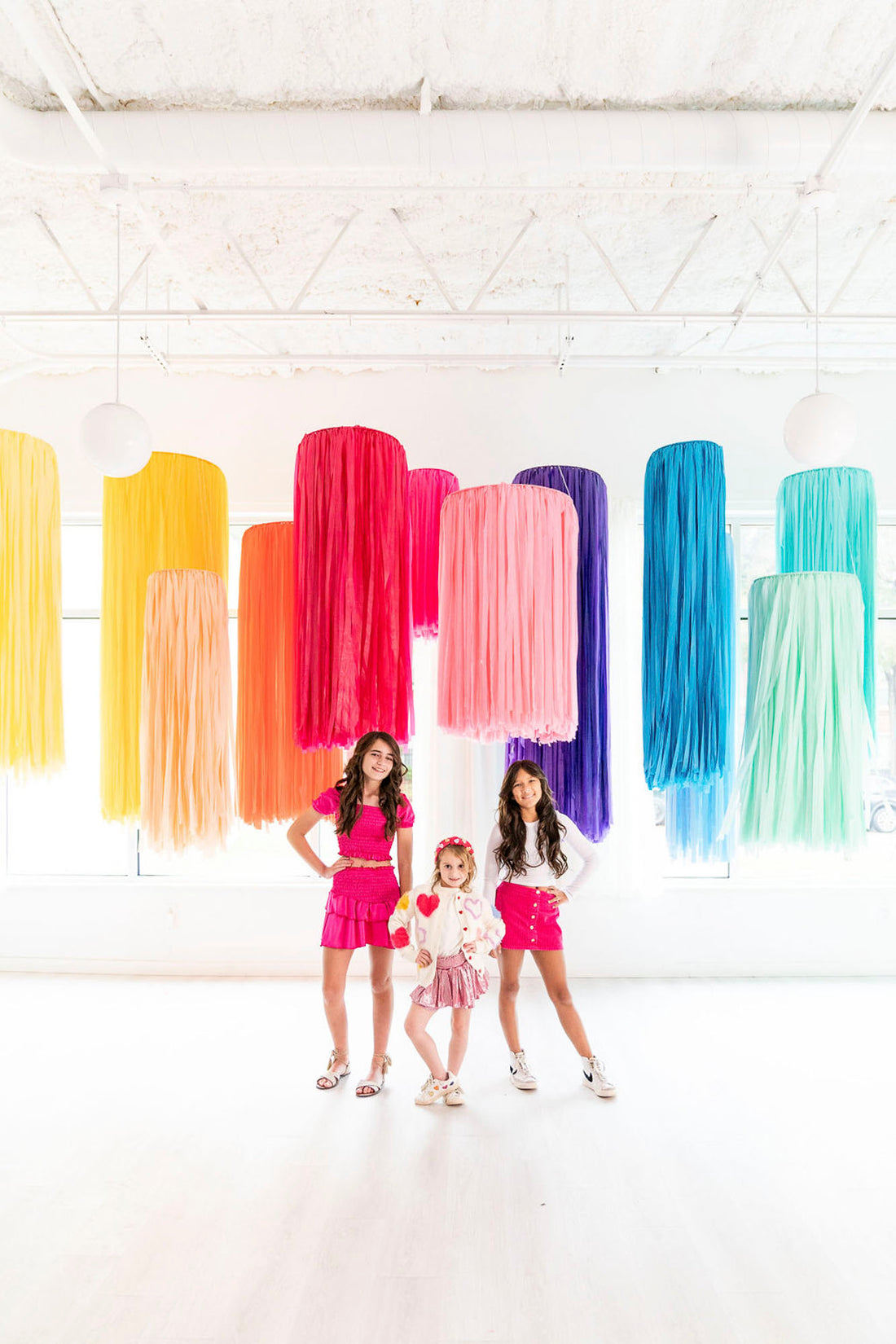 Girls posing in front of rainbow fringe aerial rings by Oh My Darling Party Co